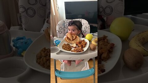 Hungry baby eats rice from bowl and refrigerator