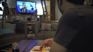 Young man eating while watching television