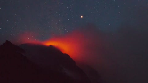 Active volcano smoking during the starry night