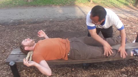 Luodong Massages White Man In Orange Shirt On Park Bench