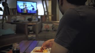 Young man eating while watching television