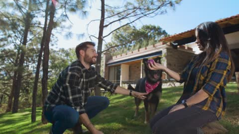 Man and woman playing with a dog in a garden