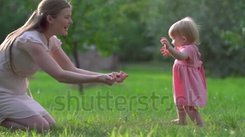 Adorable toddler hardly keeping balance in her first steps to mother.