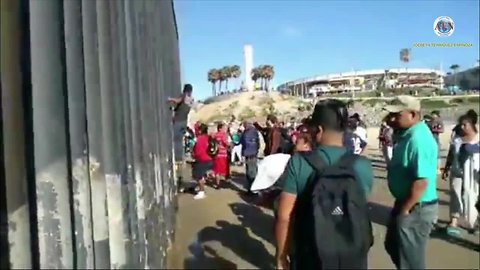 Migrants climb over border fence at Border Field State Park
