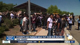 Students and parents walk out over bus routes