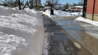 Crews work to clear snow from sidewalks in the Village of East Aurora after snowstorm