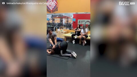 Jovem solta um pum durante alongamentos com o personal trainer