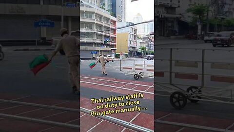 Manually closing a train crossing in downtown Bangkok