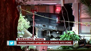 Woman pinned after truck crashes into home