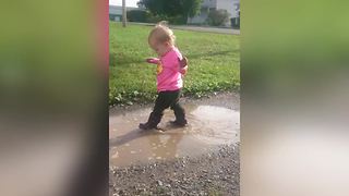 A Tot Girl Runs Into The Bumper Of A Car While She Walks In Puddles