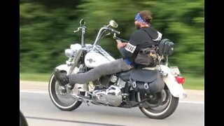 Biker takes both hands off handlebars to use phone