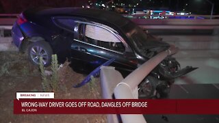 Wrong-way driver goes off road, dangles off bridge