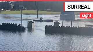 Hilarious moment man is seen kayaking through flooded car park