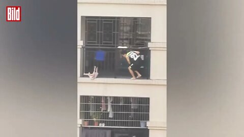 Kind zwängt sich durch Metallstäbe und hängt vom Balkon runter China