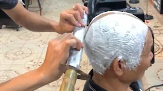 Barbeiro raspa a cabeça de cliente com uma espada