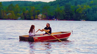 Young couple rowing boat on Quebec lake.
