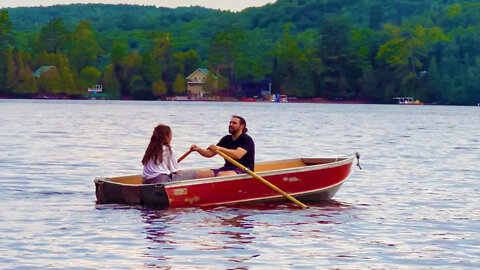 Young couple rowing boat on Quebec lake.