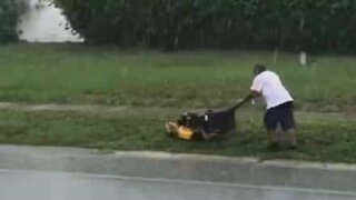 La pluie n'empêchera pas cet homme de tondre sa pelouse