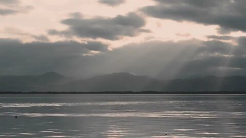 Wonderful seascape at sunset. Avki Calm ocean surface and swimming birds against distant mountains