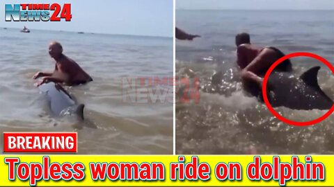 Topless woman ride on dolphin in the sea in Netherlands