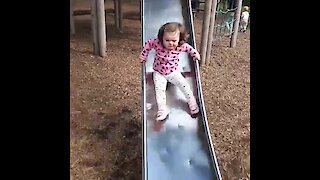 Little girl totally wipes out going down slide