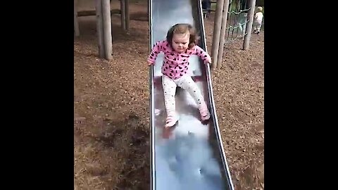 Little girl totally wipes out going down slide