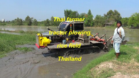 Tractor plowing rice field in Thailand