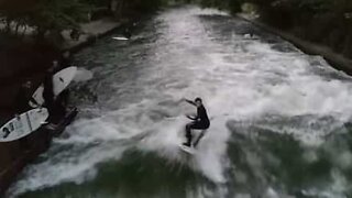 Jovem pratica surf em um rio de Munique