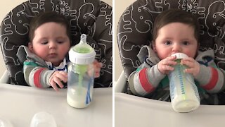 Determined baby attempts to hold bottle on his own
