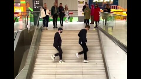 Two dancing men doing an unusual surprise to people walking around the mall