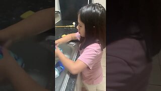 Cutie little girl washes dishes for her daddy