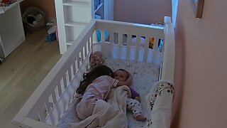 Sweet Little Girl Cuddles Baby Sister In Her Crib