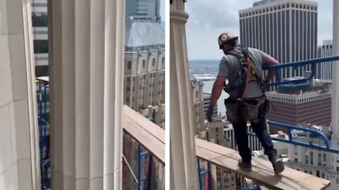 Worker walking over the skyscraper without tie his harness