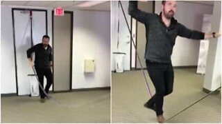 Homem pratica slackline no meio do escritório