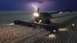 Man dances on top of combine harvester during thunderstorm