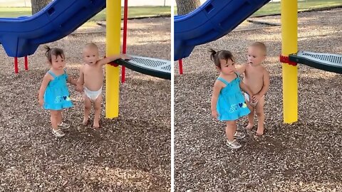 Sweet baby boy holds hands with little girl at the park