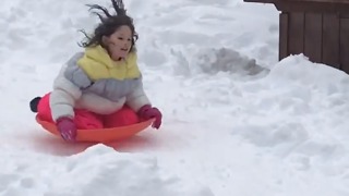 Little girl sleds down hill onto a table and falls off!