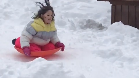 Little girl sleds down hill onto a table and falls off!