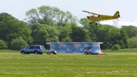 Stunt plane successfully lands on a moving trailer