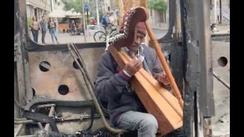 Chilean musician plays harp in burned-out bus