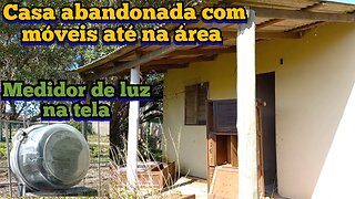 casa abandonada com pátio inundado, móveis até na área e medidor de luz na cerca