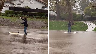 Resident paddleboards through flooded streets of Goleta, CA