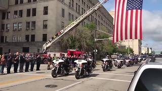 Procession for fallen officer passes under massive American flag