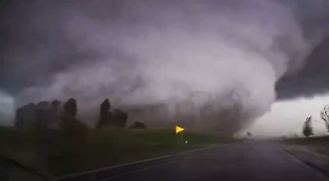 Gigantic tornado crosses the road directly in front of two travelers.