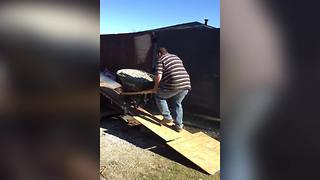 A Man Fails To Push A Full Wheelbarrow Up A Makeshift Ramp