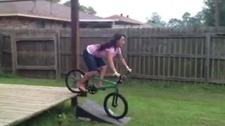 A Woman Rides A Bike Up A Ramp And Falls