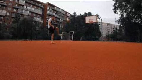 Jovem encesta bola de basquetebol com os pés