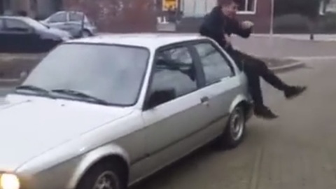 Guy goofing around on top of car receives instant karma