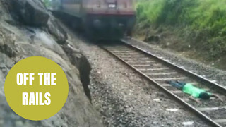 Man lays down on a railway track while a train speeds over him