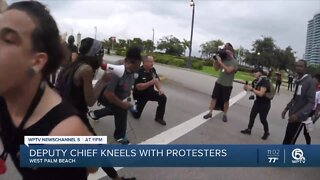 West Palm Beach Police Deputy Chief Rick Morris kneels with protesters